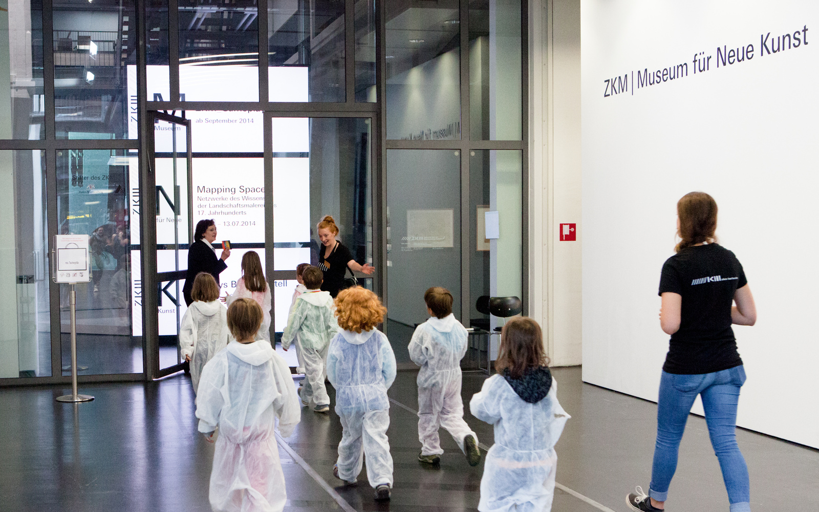 Kinder in weißen Overalls betreten das Museum für Neue Kunst