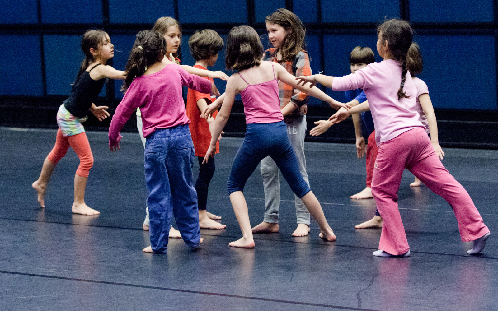 Eine Gruppe von Kindern bei einem Tanzworkshop stehen in einer lockeren Kreisformation.