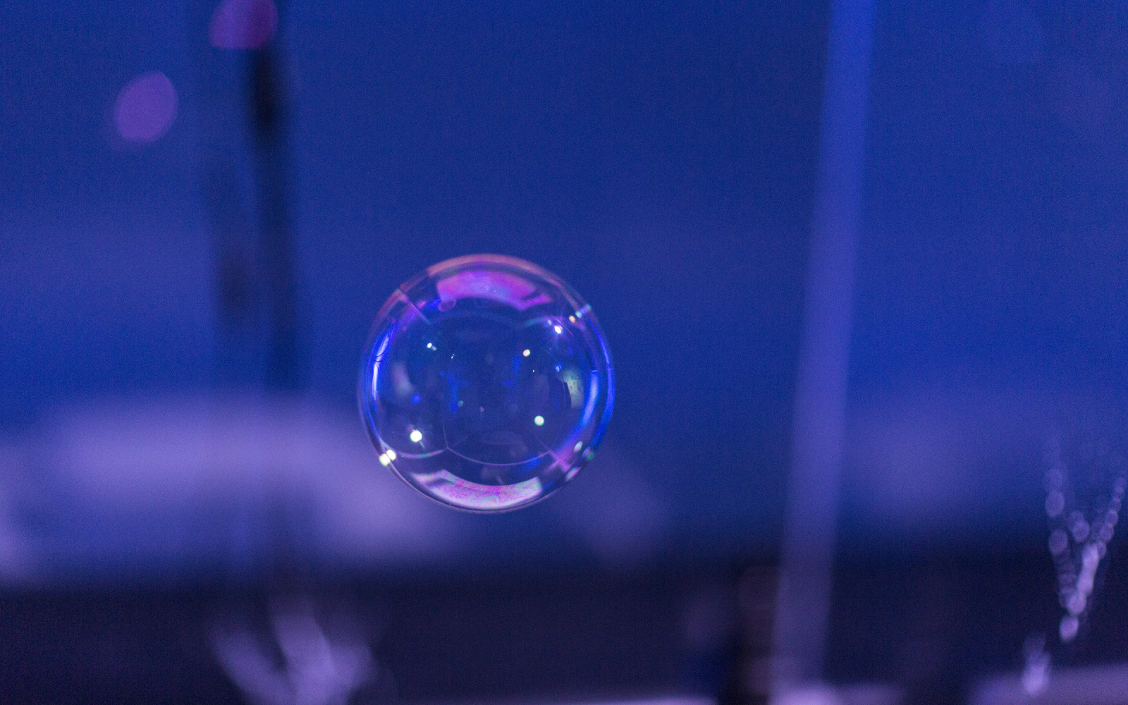 A soap bubble against a violet, dark background. 