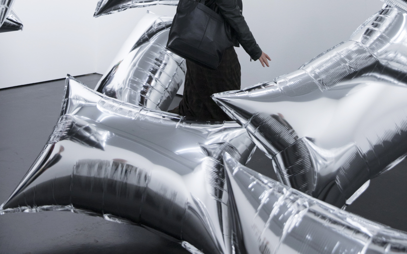 A young woman with rectangular silver balloons floating through a white room.