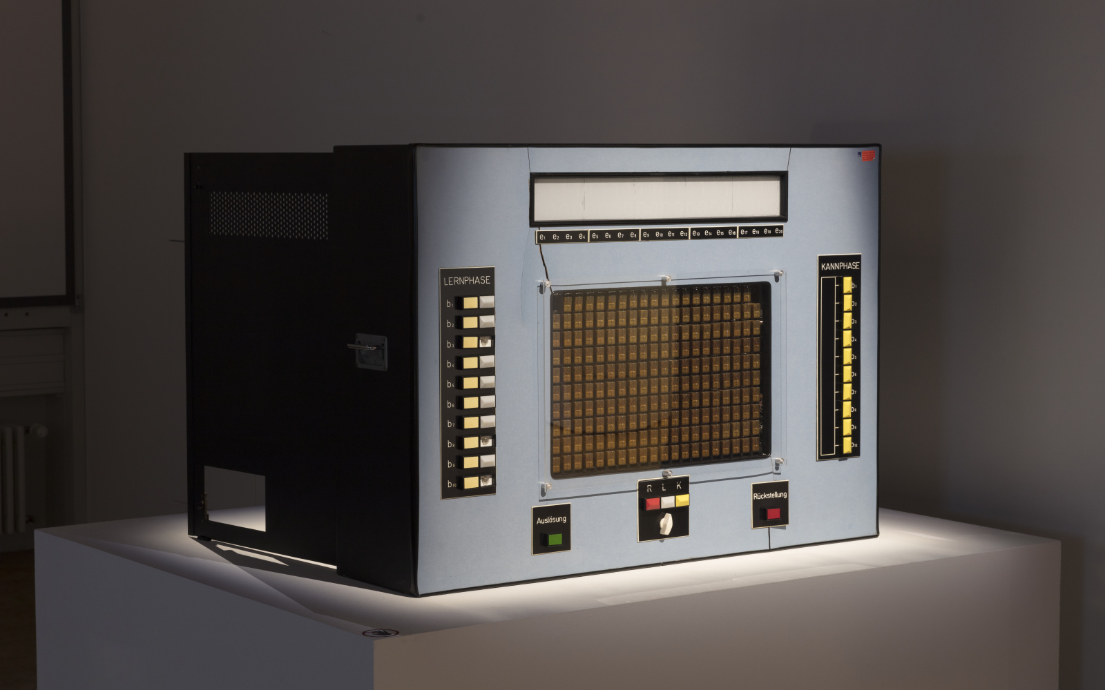 A learning computer from the 60s, rectangular, in grey and with many buttons.