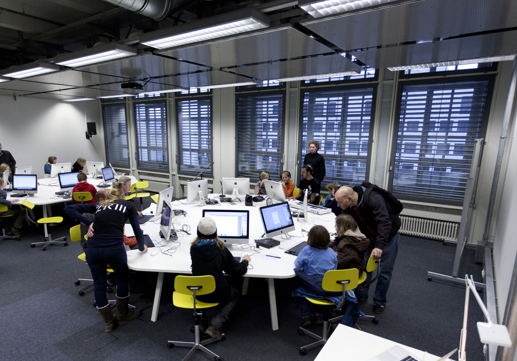 Mehrere Personen sitzen an einem rundem Tisch an Computern