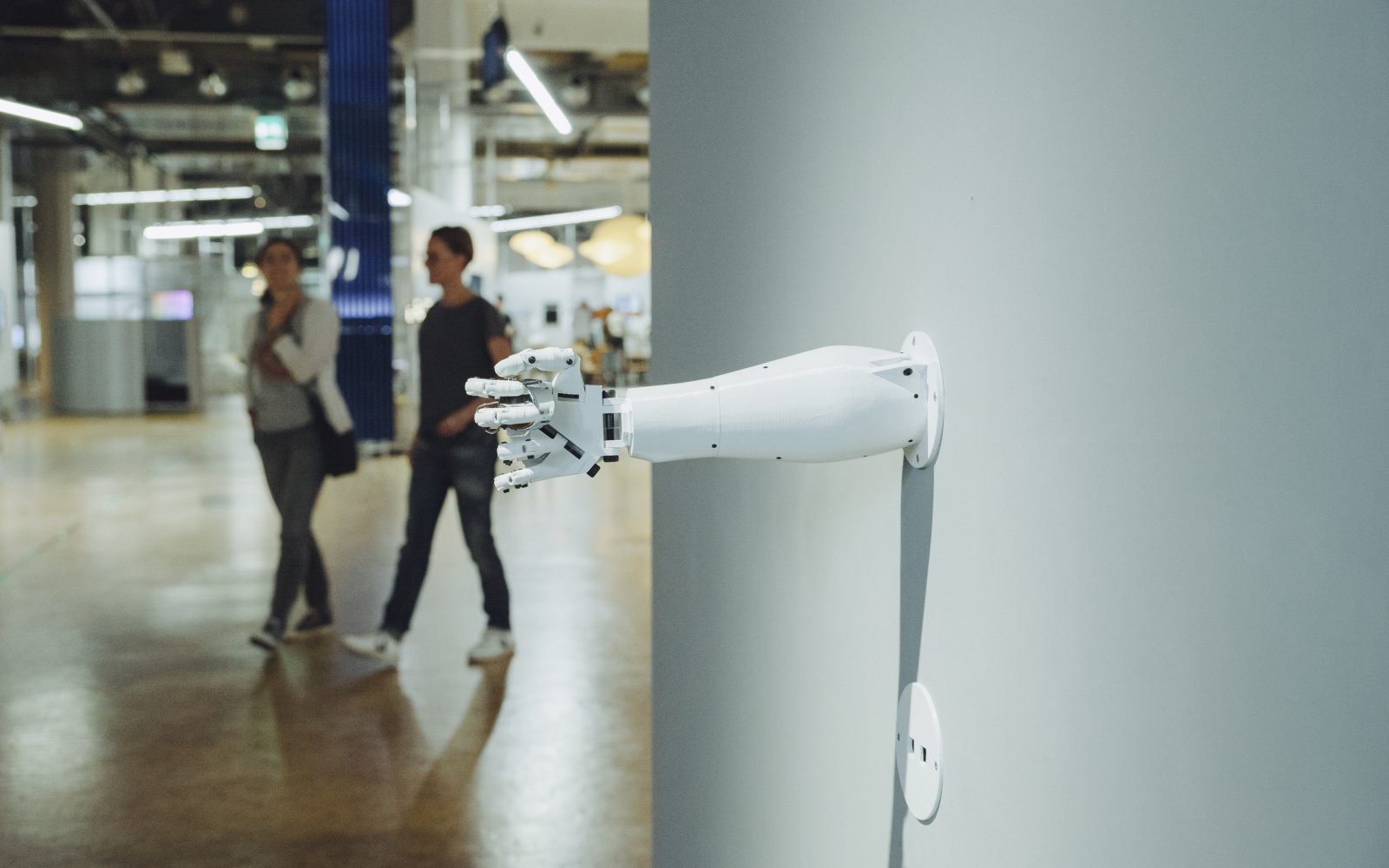 A robot arm protrudes from a wall whose hand holds something enclosed.