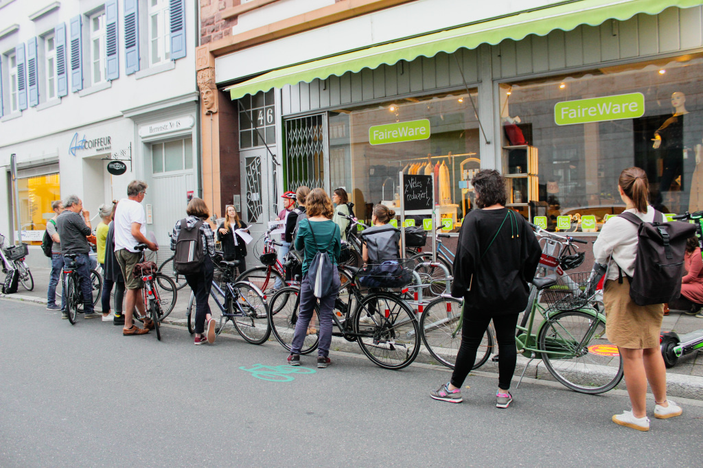 A group of poeple gathering in front of a shopping window with their bycicles