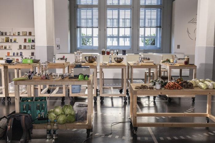 There are wooden tables with food and kitchen tools standing in the ZKM exhibition »Critical Zones«.