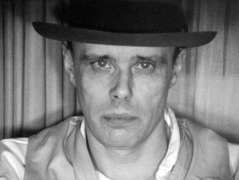 A black and white portrait of the artist Joseph Beuys.