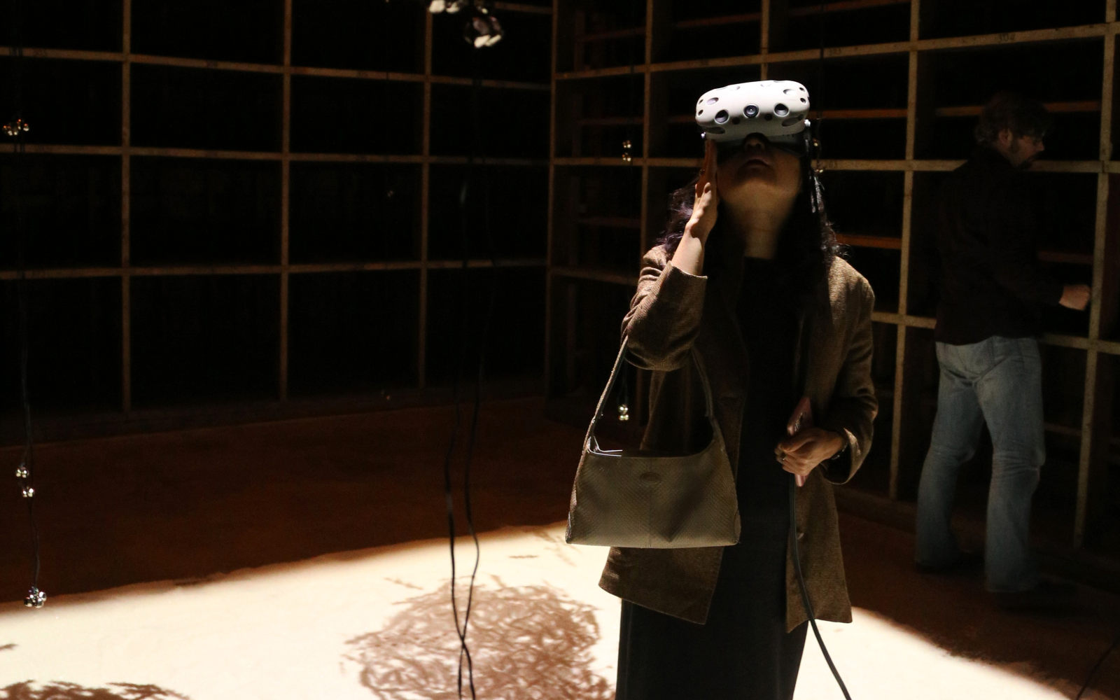 A visitor in a darkened room looks up at the ceiling through VR glasses.