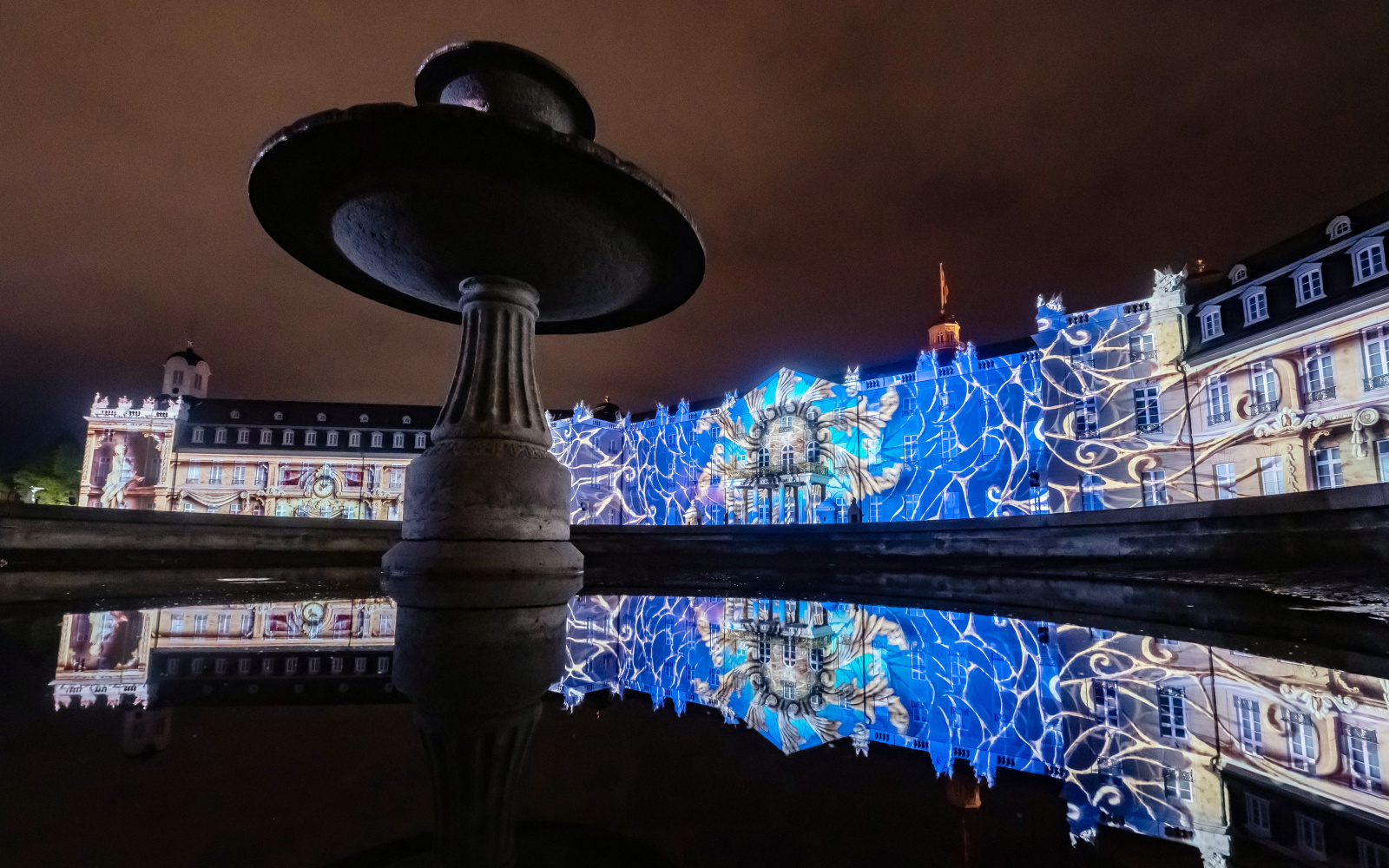 Photo of a colorful projection mapping at night on the baroque Karlsruhe castle.