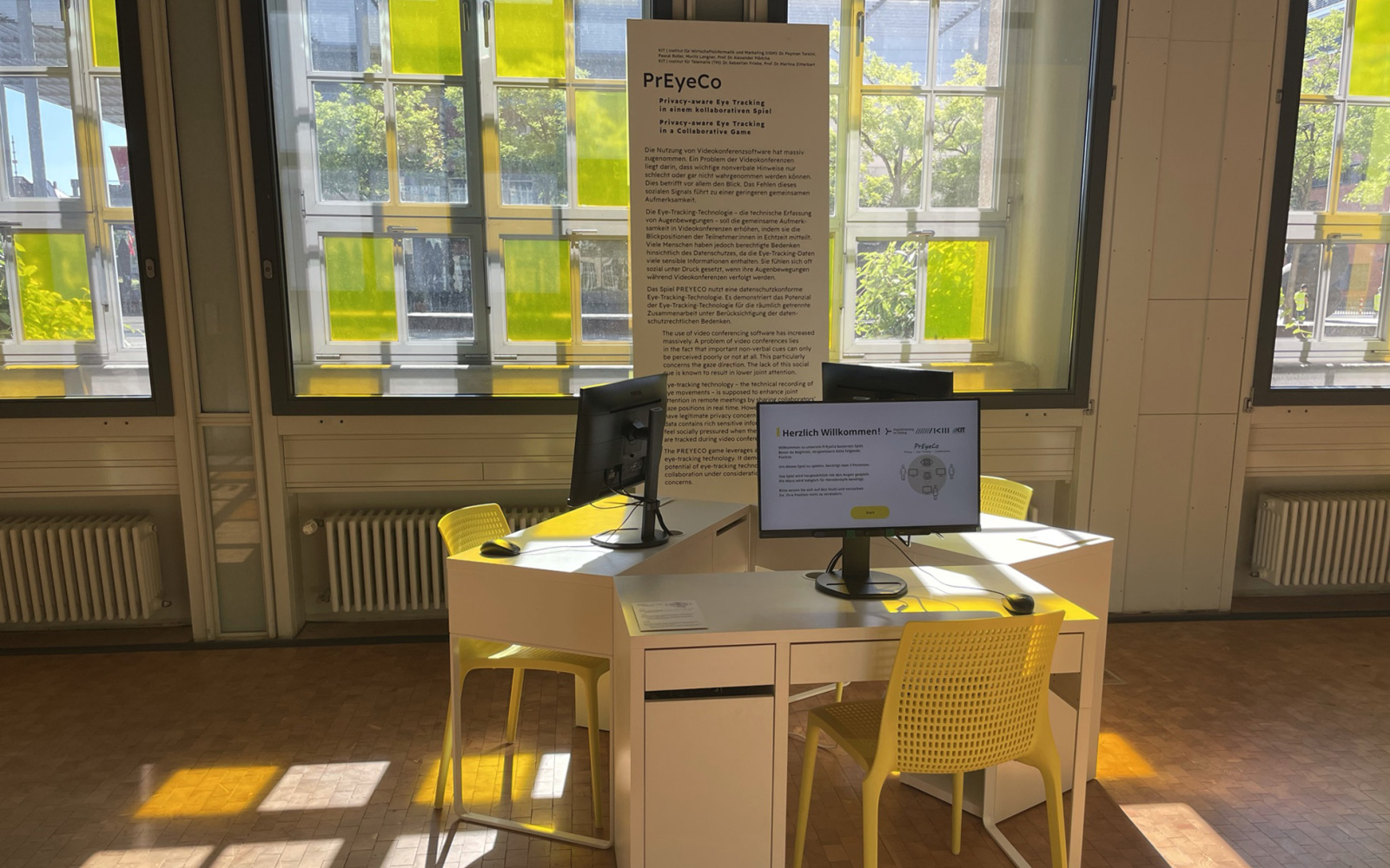 Ausstellungsansicht vom Werk PrEyeCo; drei Schreibtische mit Computern und gelben Stühlen