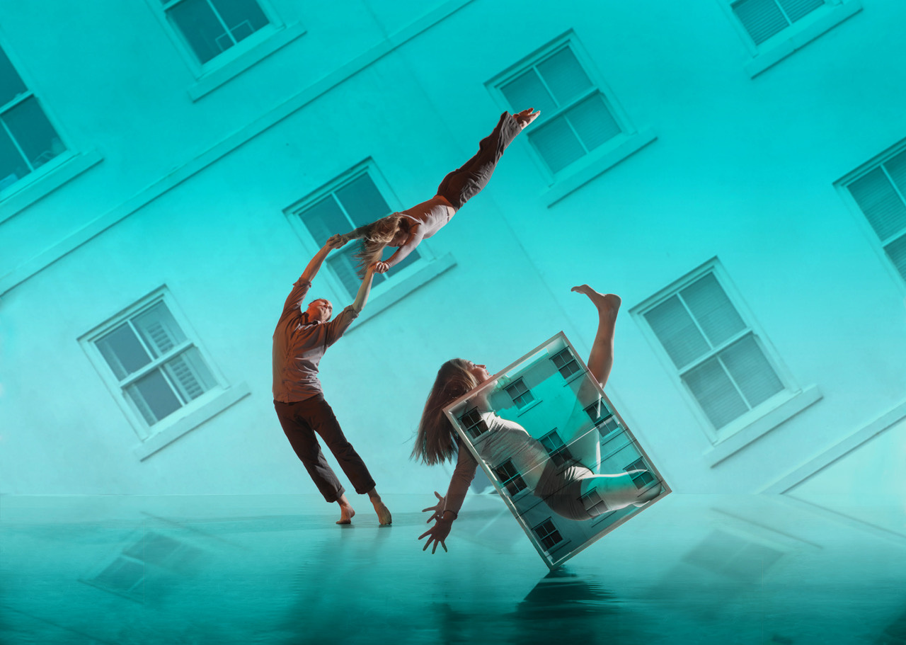 You can see 3 dancers in front of a turquoise-colored, slanted house facade.
