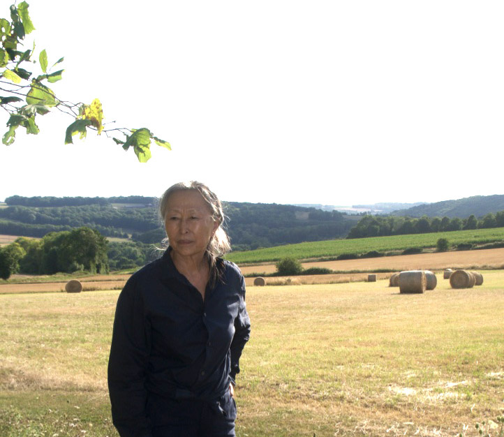 Zu sehen ist ein Foto von KIM Soun Gui, die auf einem Feld steht.