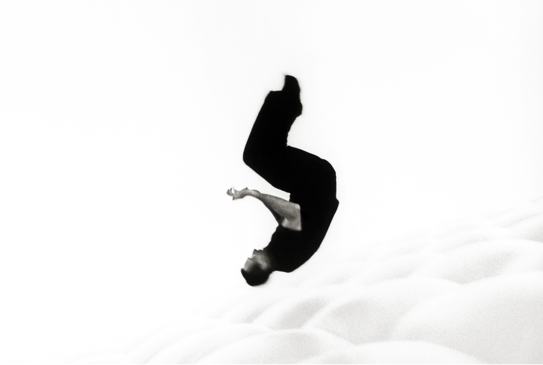 You can see a person dressed in black doing a roll in the air. The background is white.