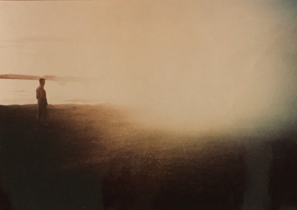 On the left side there is a man standing in front of a sea. On the right, the image is heavily overexposed.