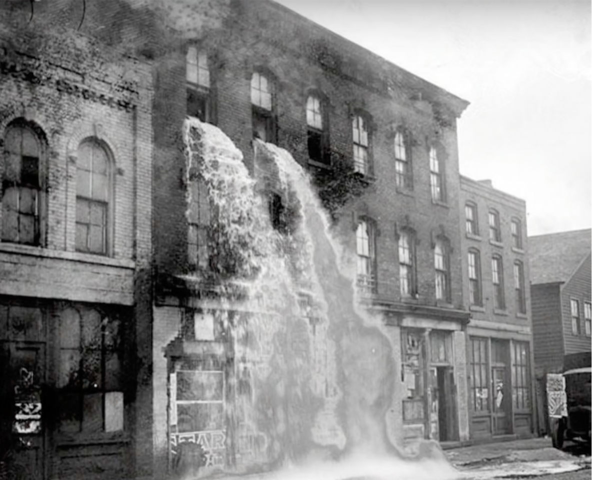 You see a factory building with a waterfall bursting out of the window in black and white.