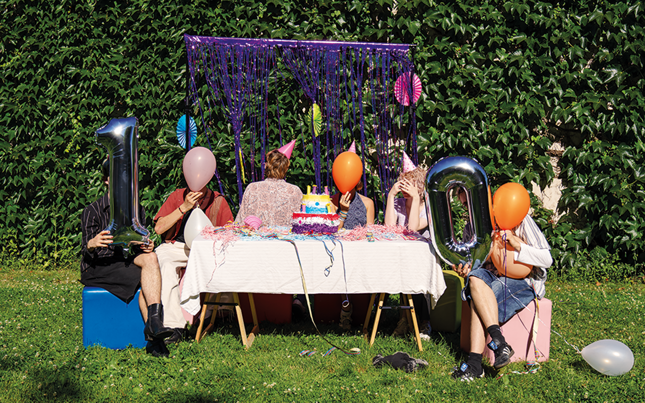 Eine grüne Wiese mit einem Tisch voller Geburtstagsdekoration und einer 10 als Luftballon