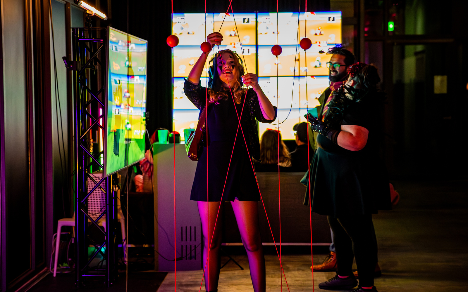 The picture shows smiling people in a colorfully lit room.