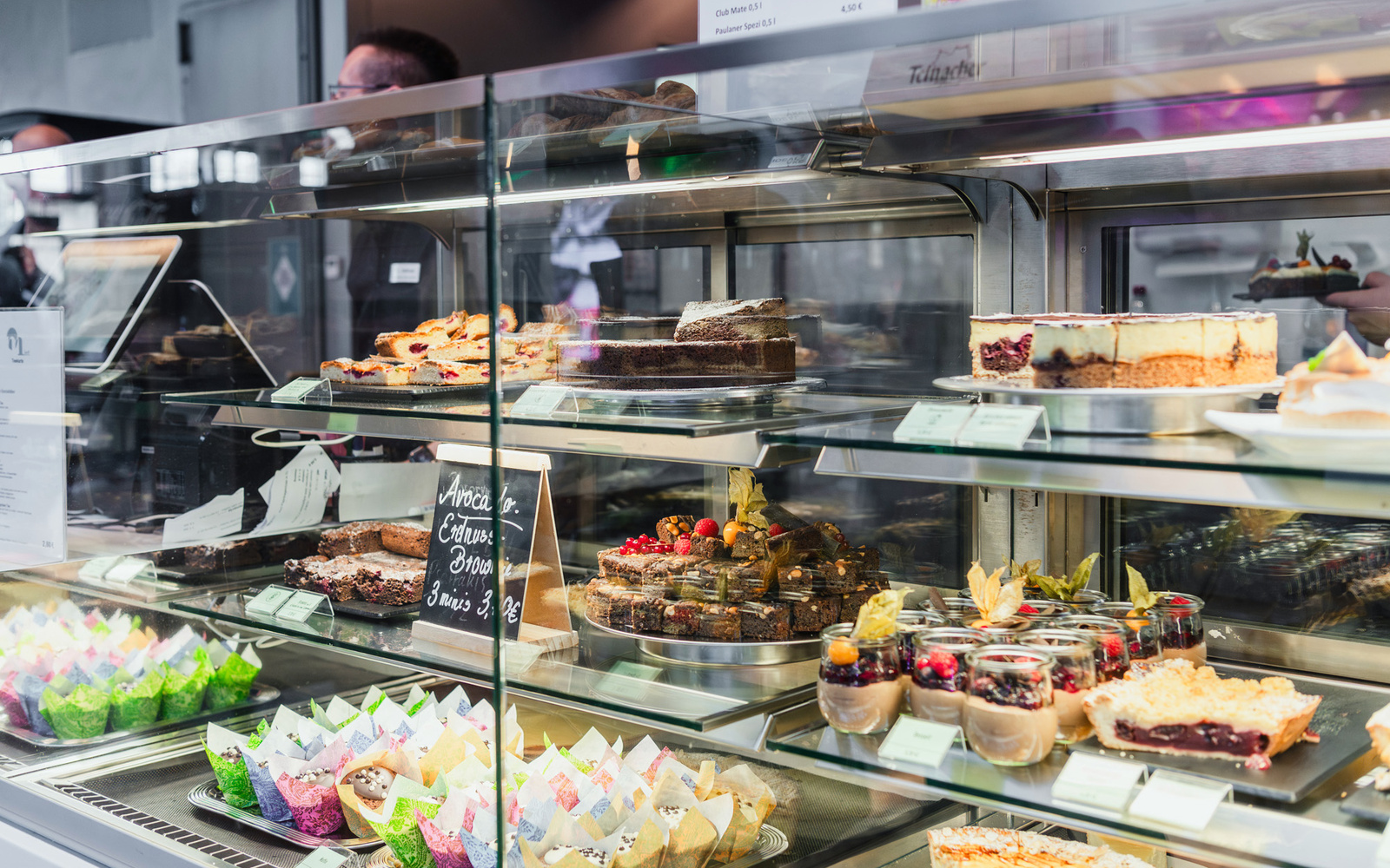 Zu sehen ist eine Theke mit verschiedenen Angeboten wie Kuchen und Muffins. 