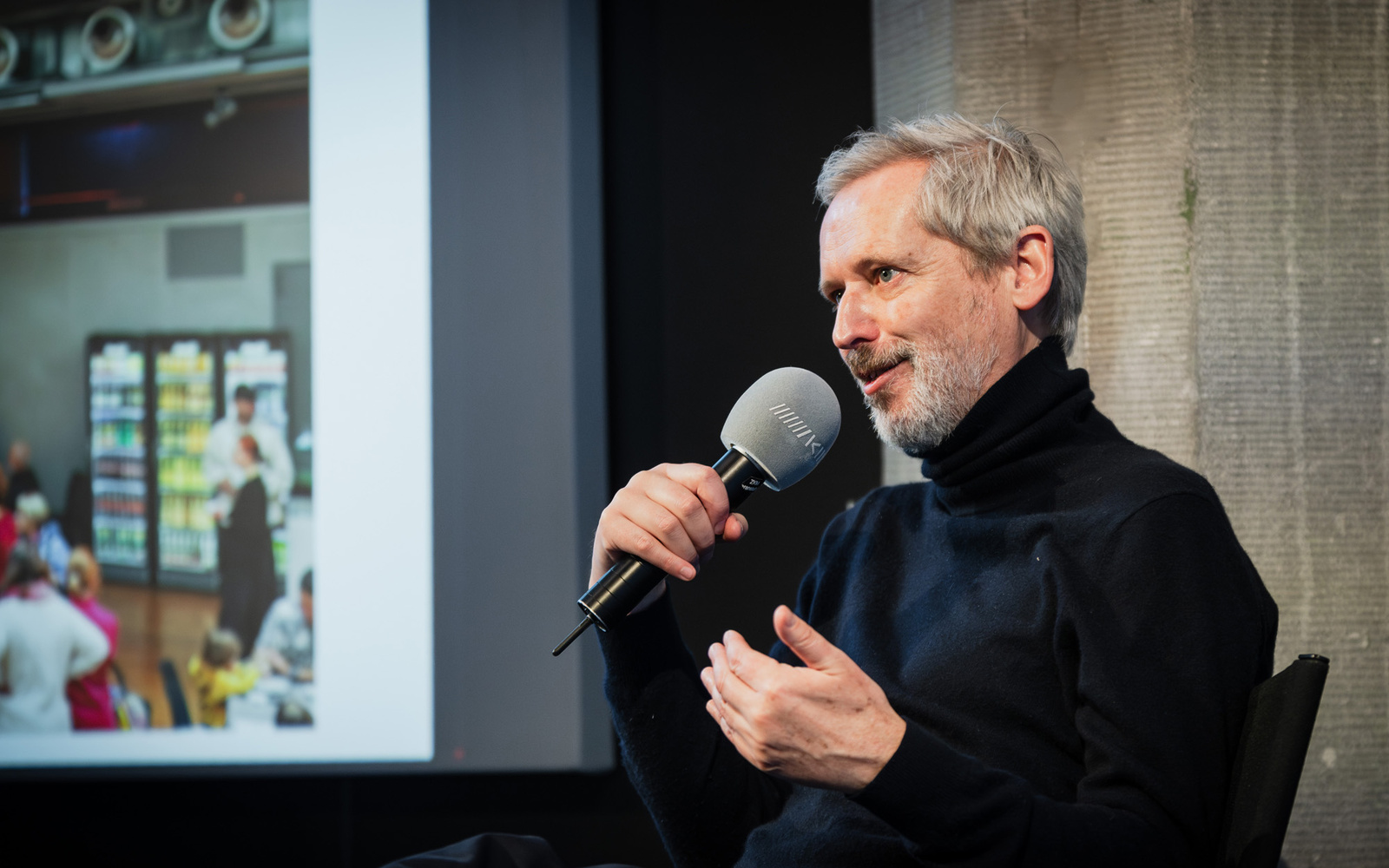 Zu sehen ist Alistair Hudson, der in ein Mikrofon spricht. 