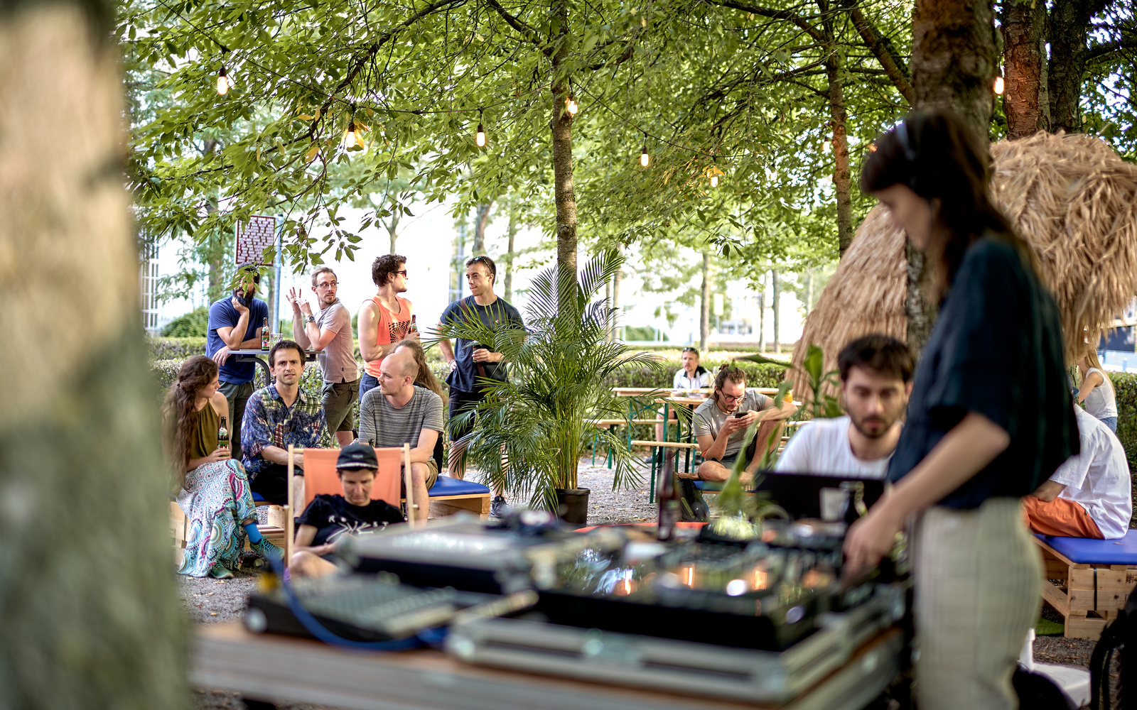 A DJane and people in the green on deckchairs behind her.