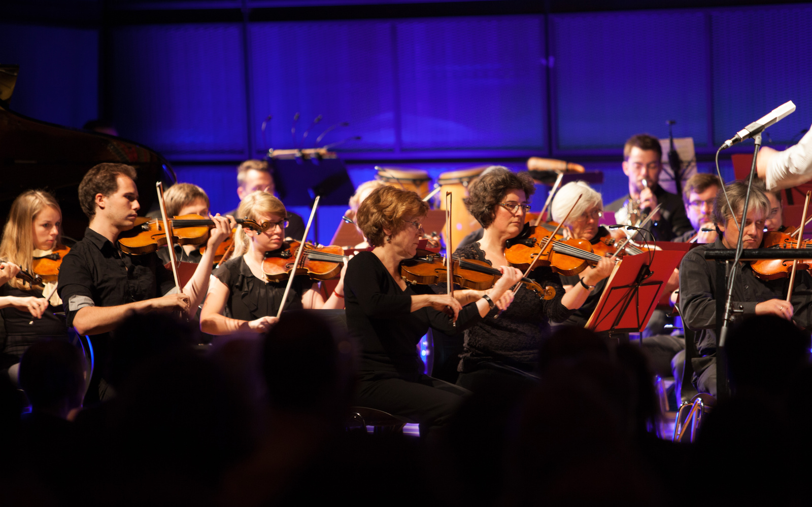 Musiker und Musikerinnen spielen Instrumente auf einer Bühne. 