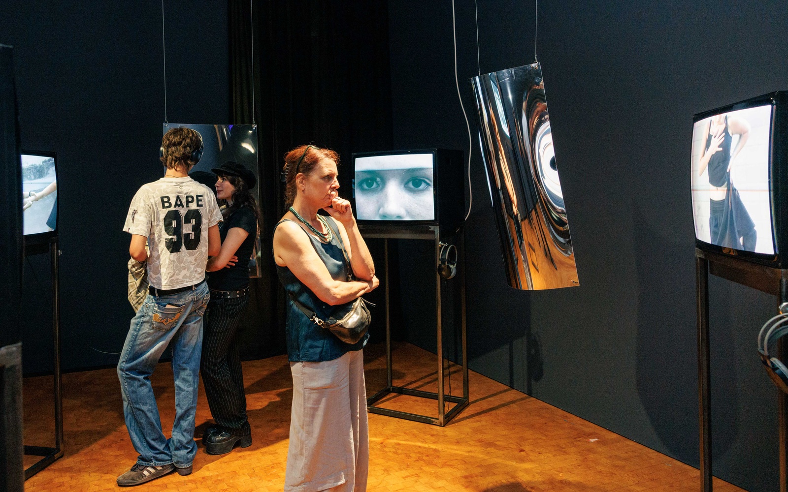 Zu sehen sind Personen, die Bildschirme in einem Ausstellungsraum betrachten. 