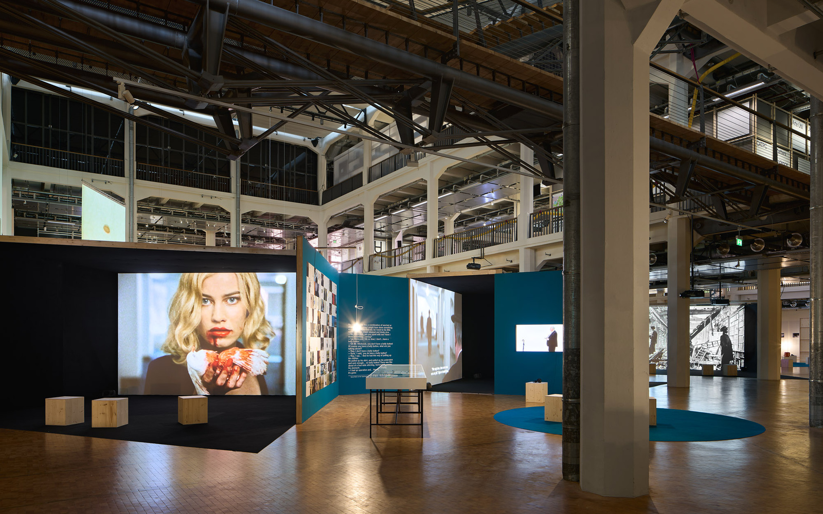 Zu sehen ist ein Ausstellungsraum in dem mehrere Filme gezeigt werden.