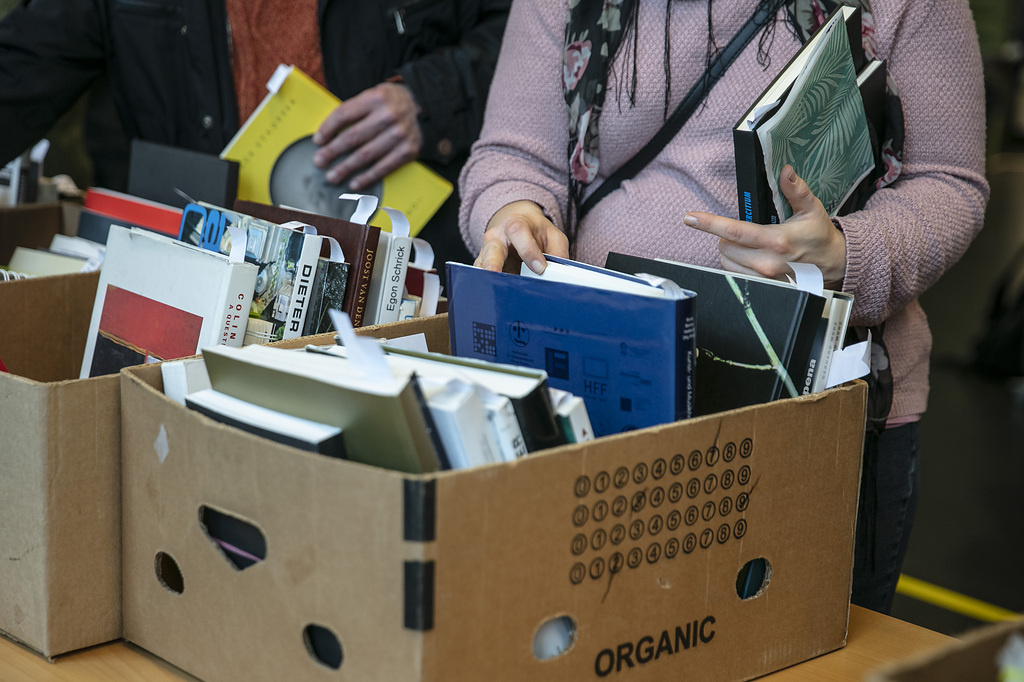 Bild einer Bücherkiste mit Händen, die danach greifen.