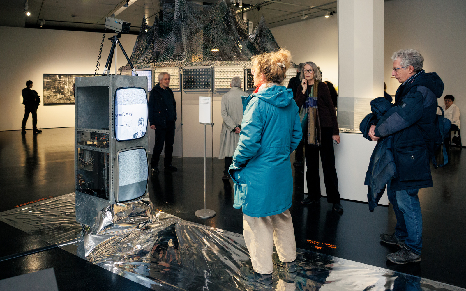 Eine Frau in blauer Jacke steht vor einem Röhrenmonitor.