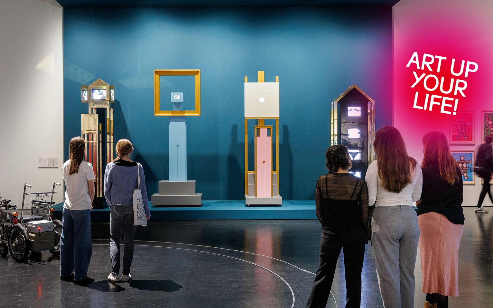 Drei Personen stehen vor einem Kunstwerk.