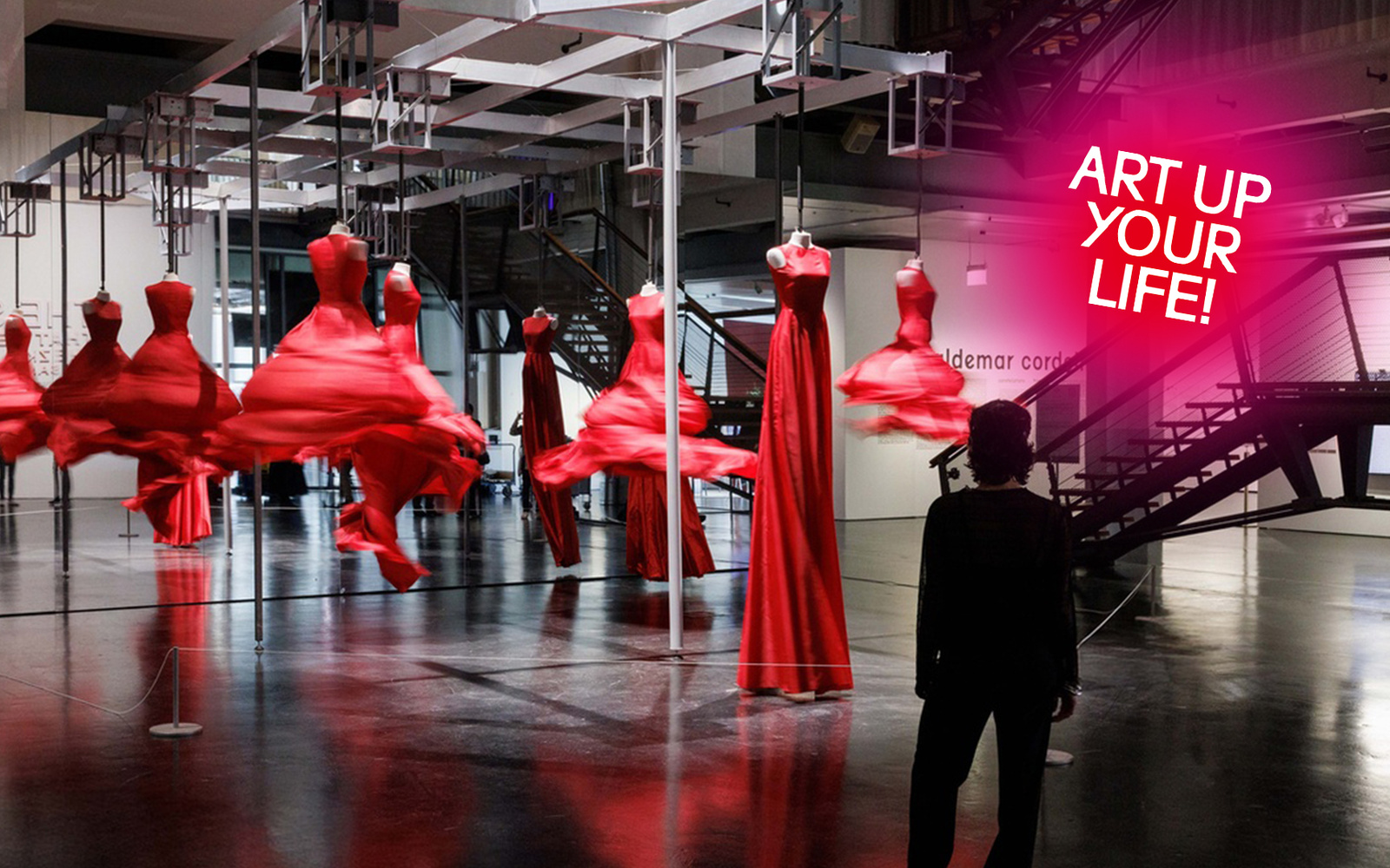 A person stands in front of spinning red dresses.