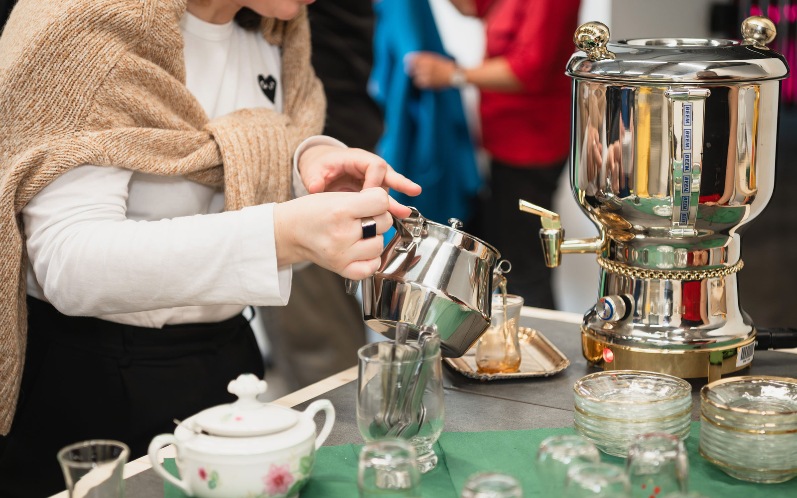 Zu sehen sind die Hände einer Person, die Tee einschenkt.  