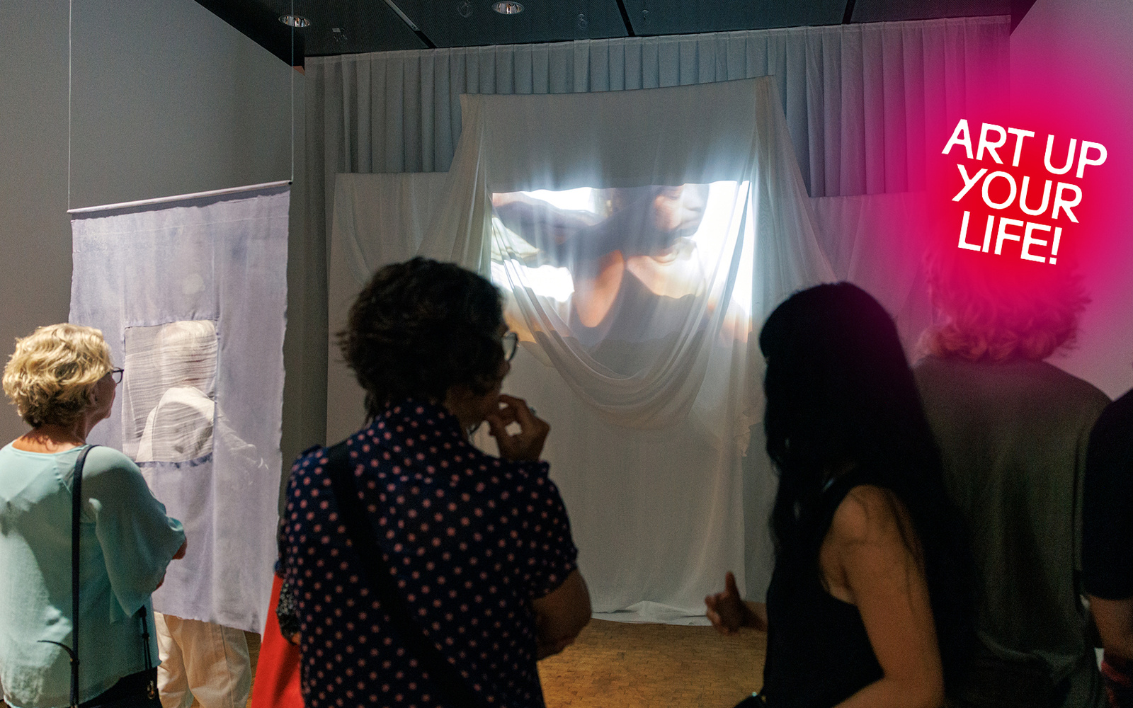 Zu sehen ist sind Besuchende, die eine Projektion betrachten.