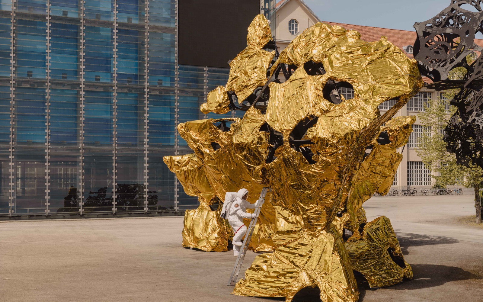 Ein Astronaut steigt vor dem ZKM Karlsruhe aus einem goldenen Gebilde.