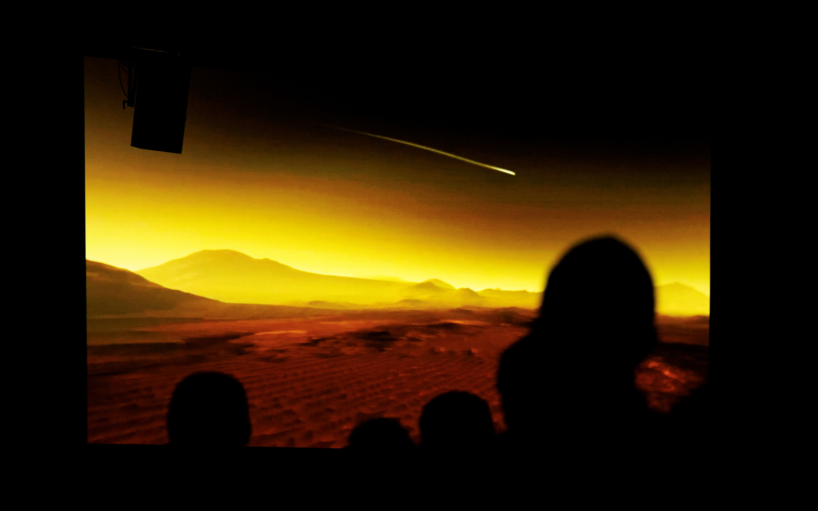 The picture shows a vast landscape with silhouettes in the foreground.