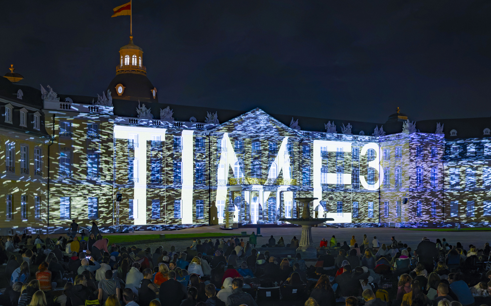Der Schriftzug "TIME³" wird auf das Karlsruher Schloss projiziert.