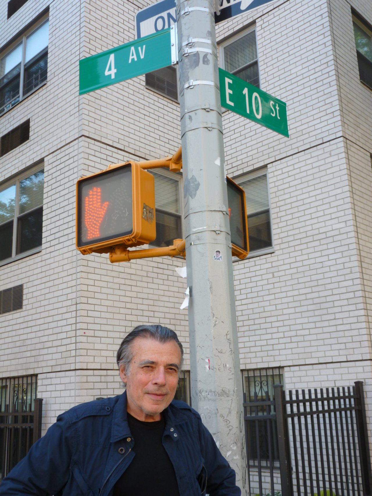 A man standing at an intersection under traffic lights with a red hand on it