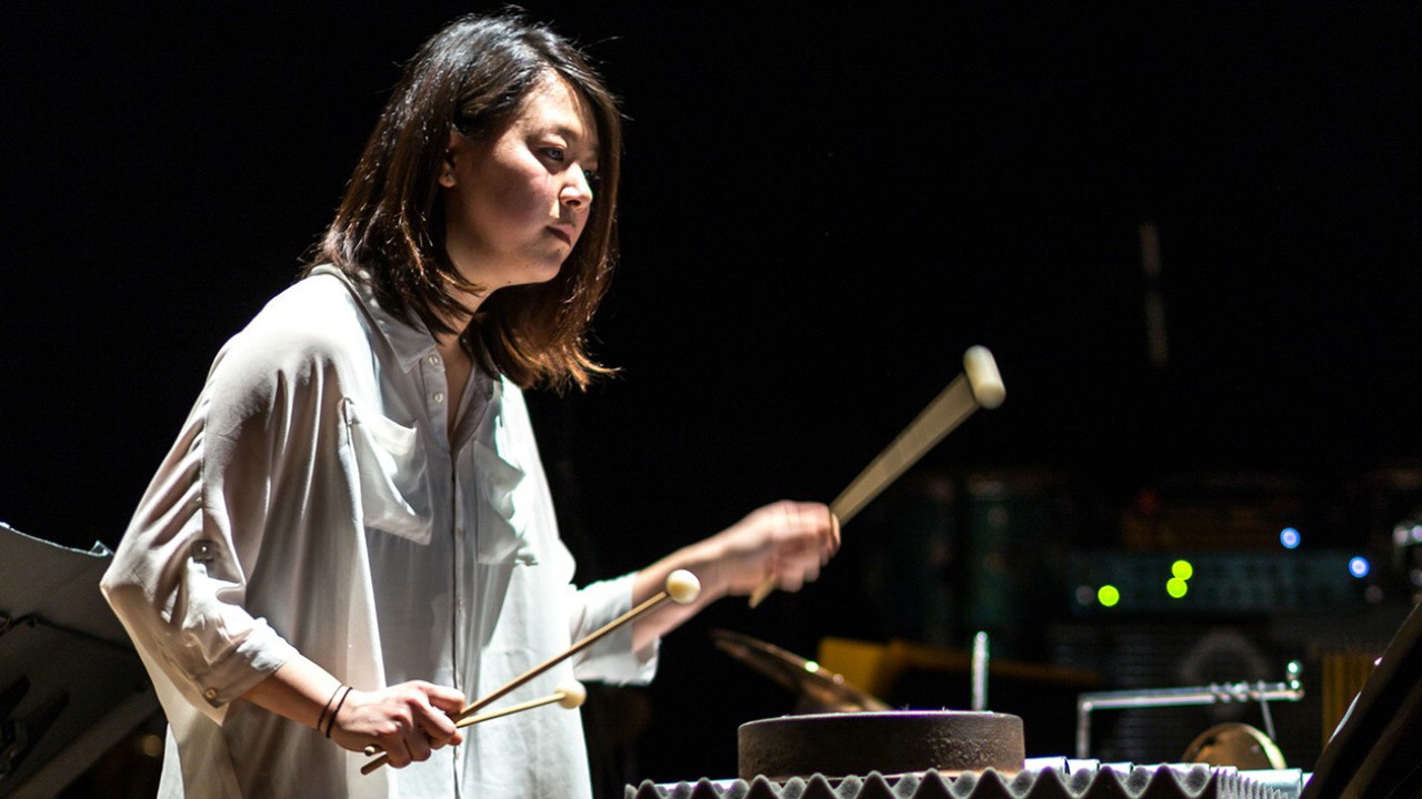  Woman with white shirt playing with drumsticks on percussion