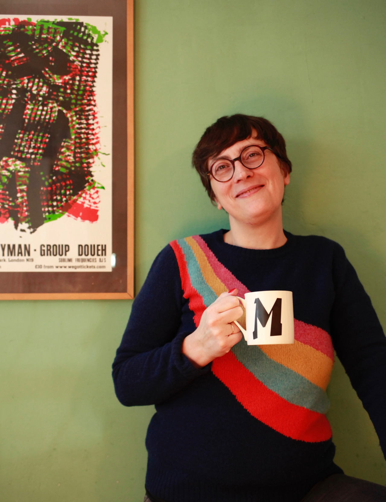 The pictures shows Marie Pierre smilying into the camera and holding a cup with the letter M on it.