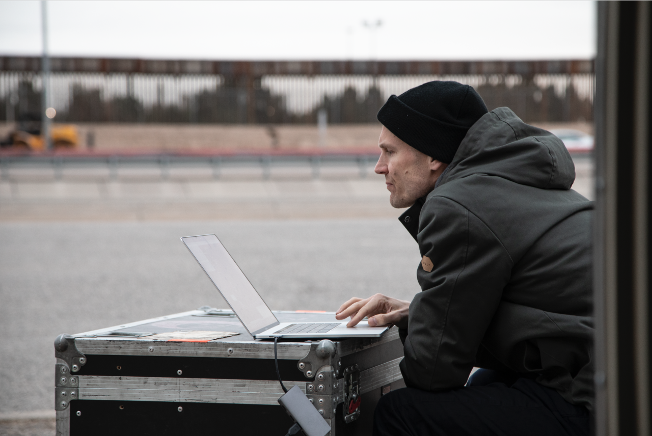 You can see Stephan Schulz sitting in front of a laptop. The laptop is standing on a black case.