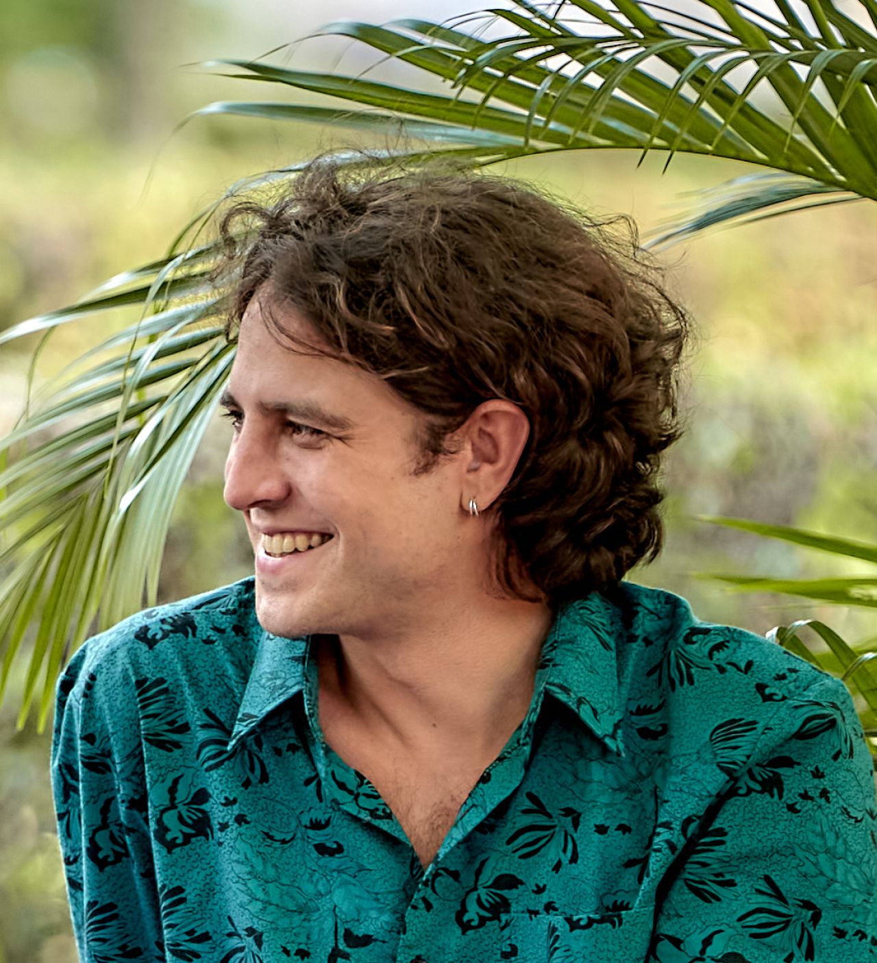 The photo shows a young brown-haired man wearing a green and flowered shirt.