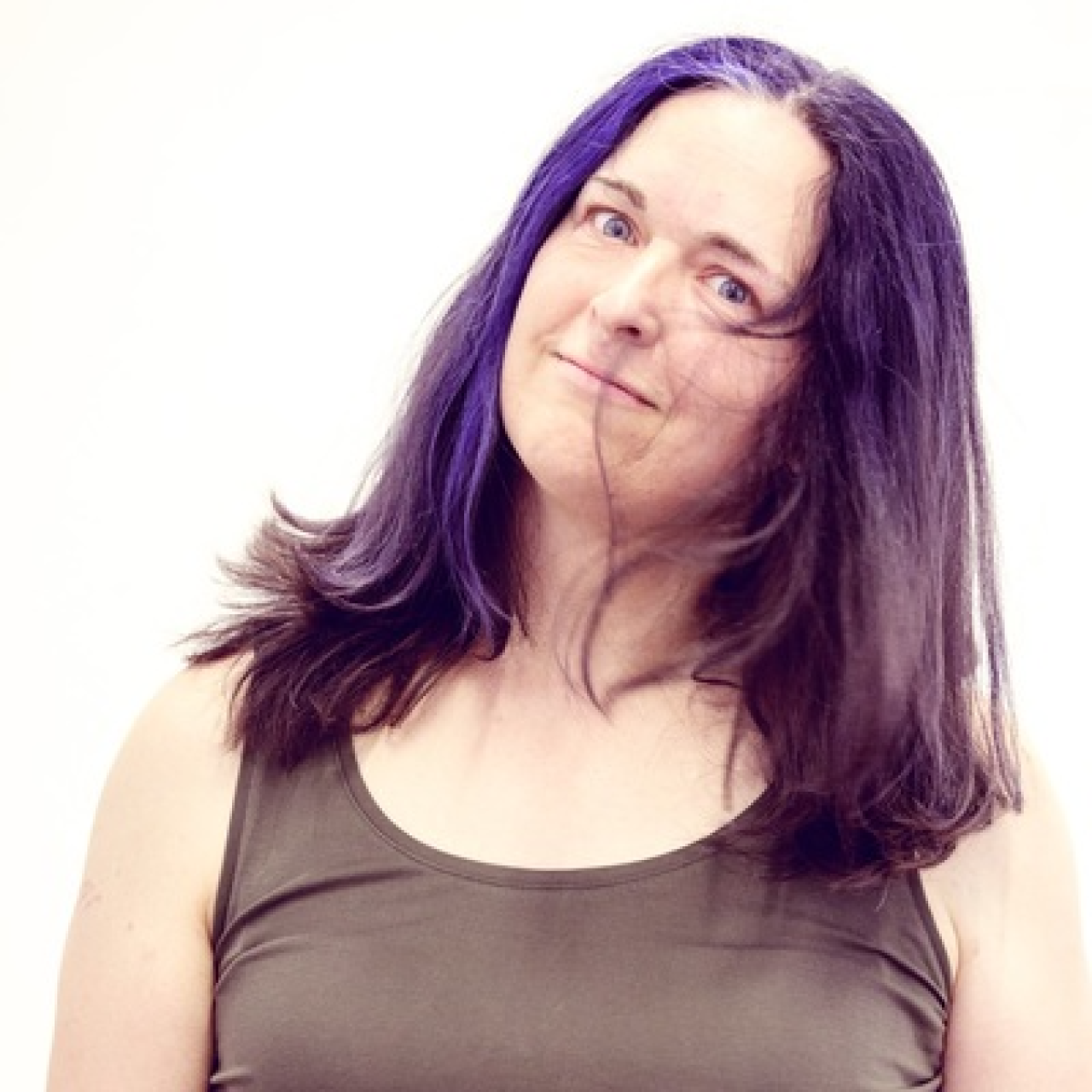 Woman with purple hair, holding her head at a slight angle.