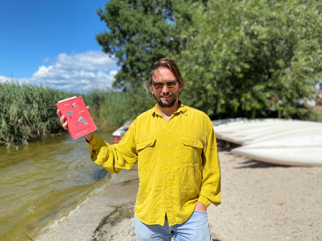 Mann in gelbem Hemd, der ein rotes Buch hält
