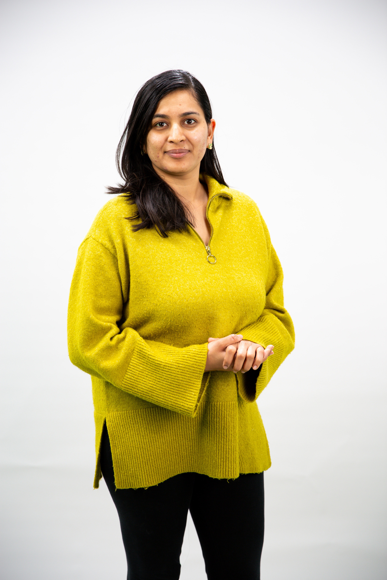 Frau mit schwarzen Haaren und einem gelben Pullover
