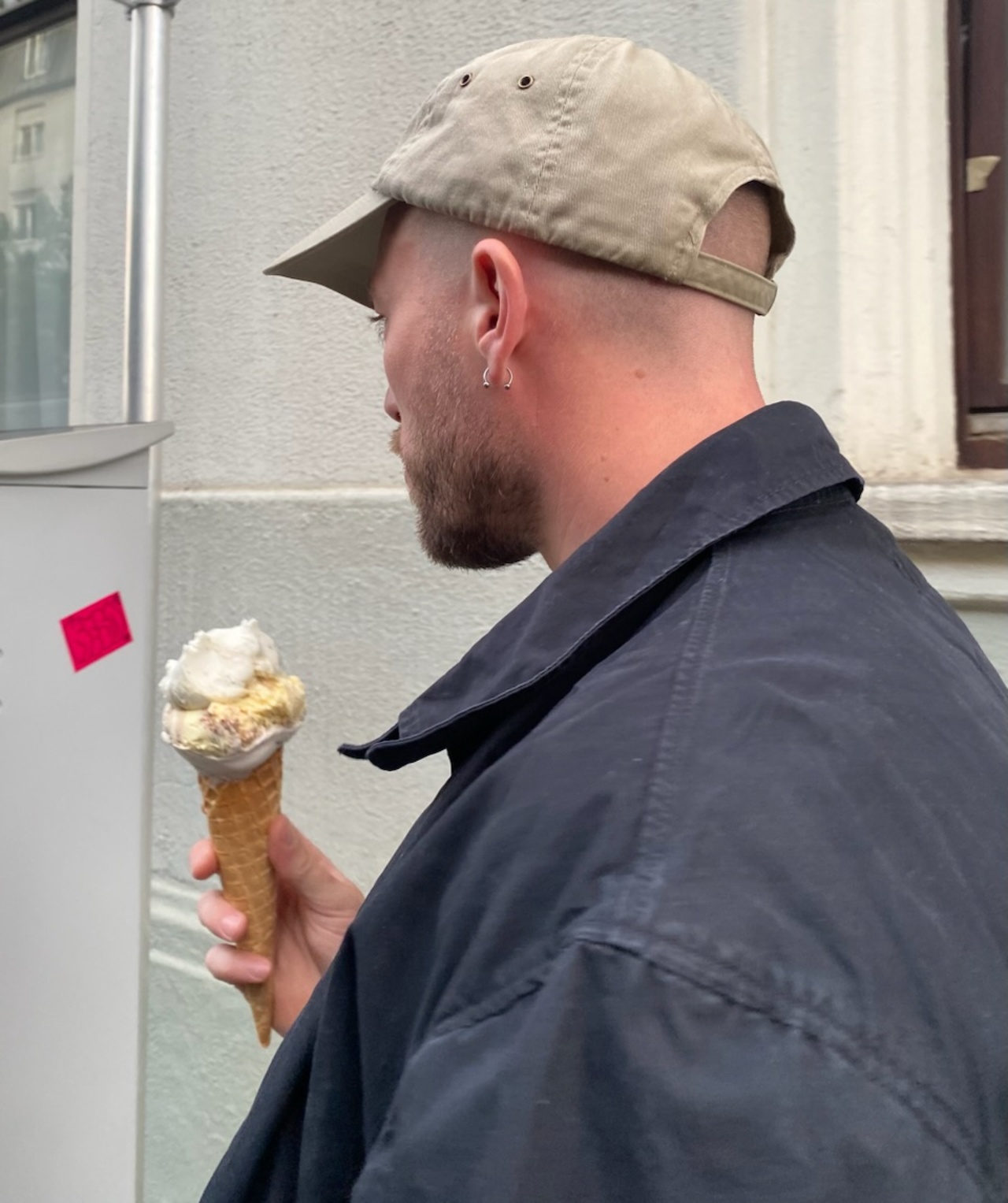 The picture shows a person holding an ice cream and wearing a cap. 