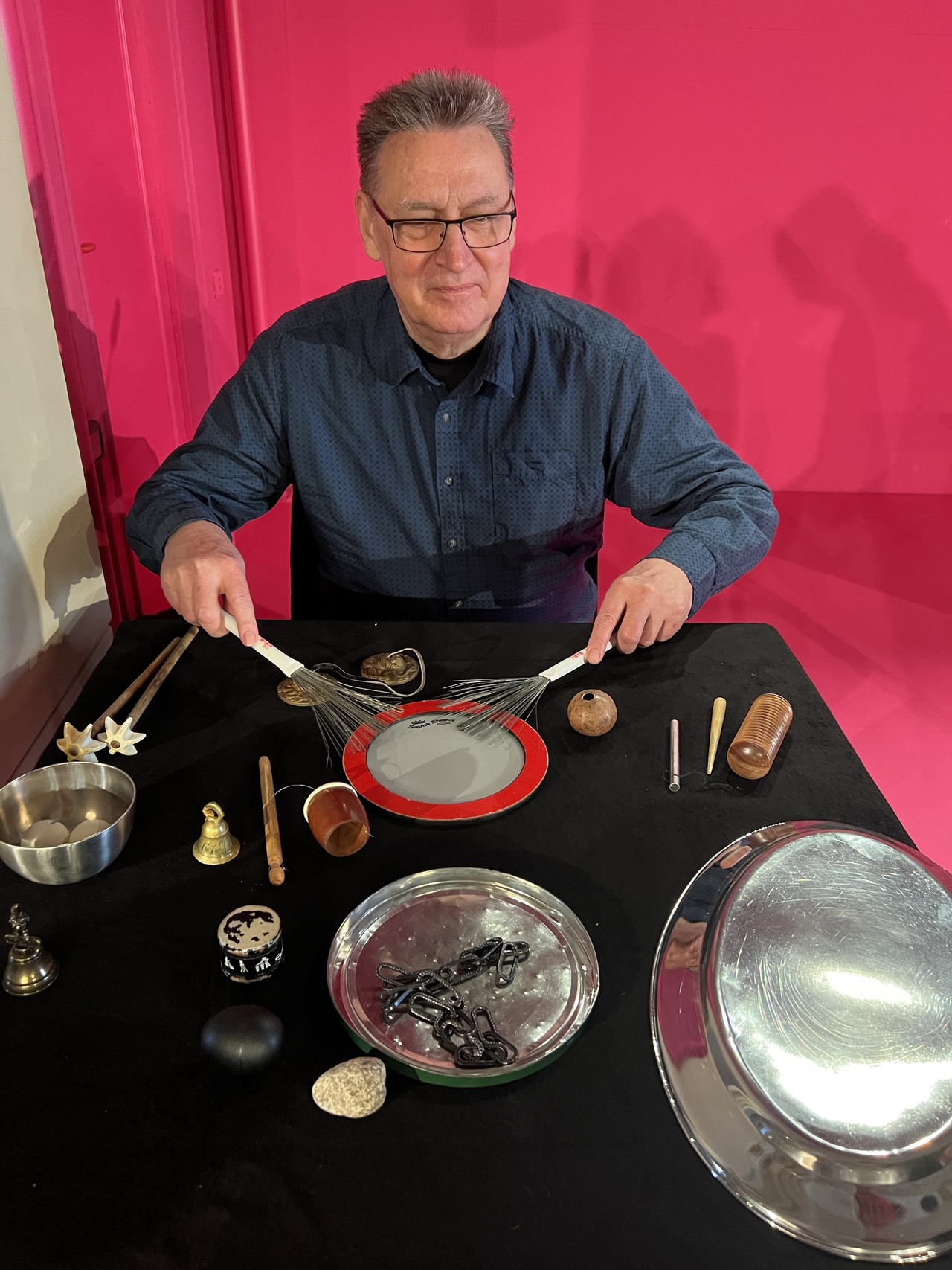 Eine Person, am Tisch sitzend, mit Musikinstrumenten.