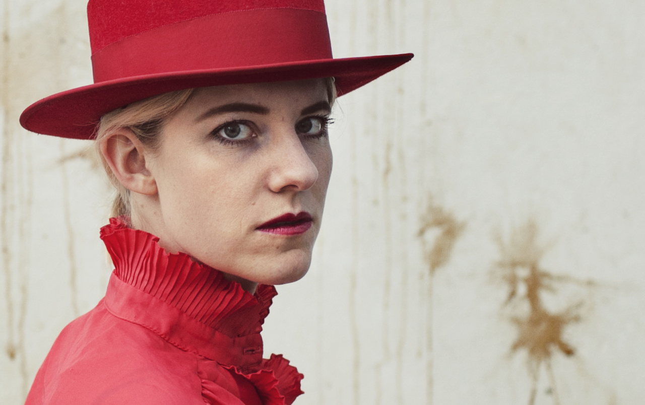 The picture shows a portrait photo of a person with a red hat. 