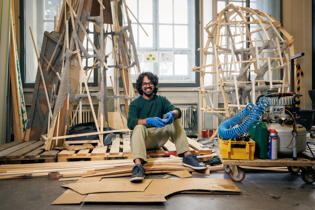 Ein Mann mit schwarzen Locken arbeitet an seinem Kunstwerk aus Holzlatten.