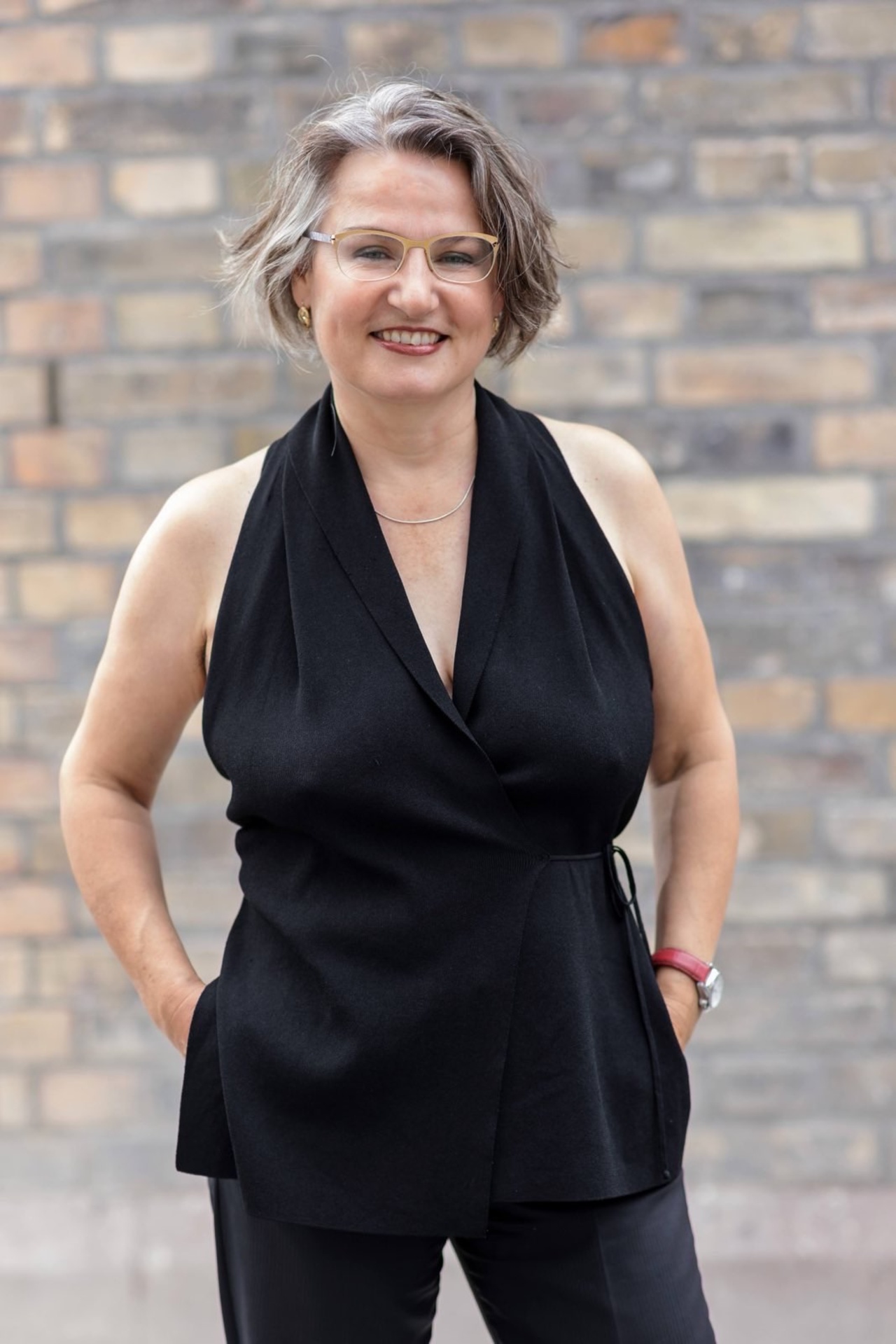 A picture shows a person standing with their hands in their pockets, smiling at the camera.