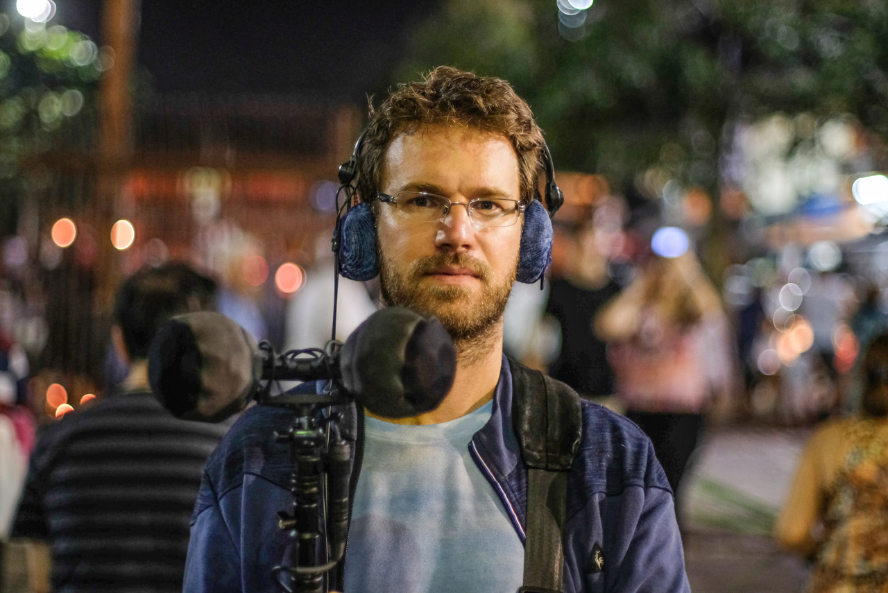 Das Porträtfoto zeigt eine Person mit technischer Ausrüstung. 