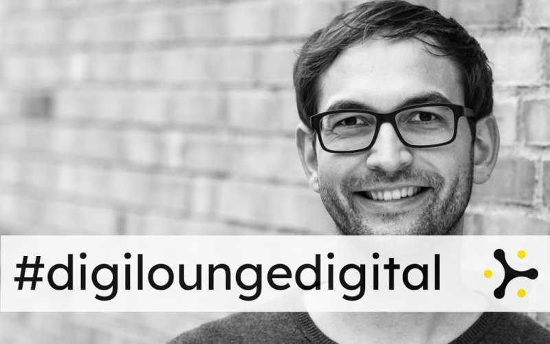 You can see a man with glasses looking into the camera. On the picture it says #digiloungedigital.